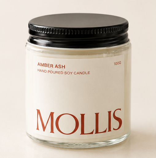 Four Mollis soy candles in clear glass jars with black lids and cream labels, arranged in a 2x2 grid on a warm beige background. The labels show different scent names: Amber Ash, Saffron Noir, Leather, and Neroli.